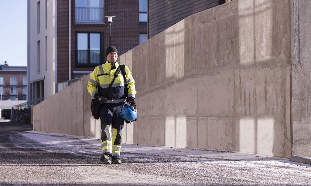 Oulun Energian työntekijä kävelee kerrostalon edessä.