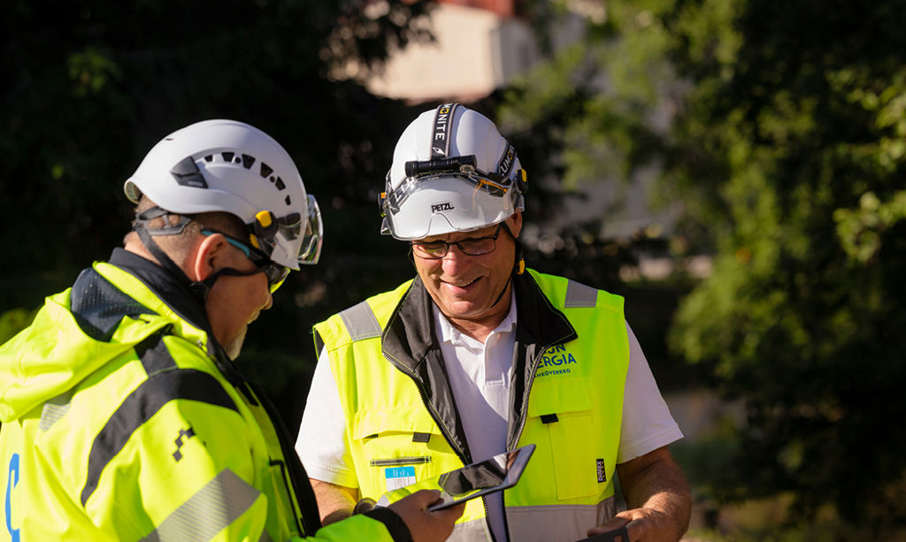 Kaksi Oulun Energian Sähköverkko Oy:n työntekijää juttelevat keskenään ulkona. 