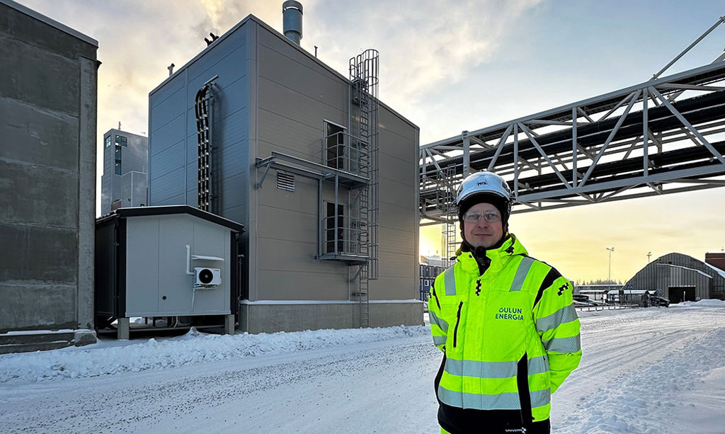 Polttoainehankinnoista vastaava Lauri Heilala seisoo ja hymyilee Sähkökattila hänen selkänsä takana.