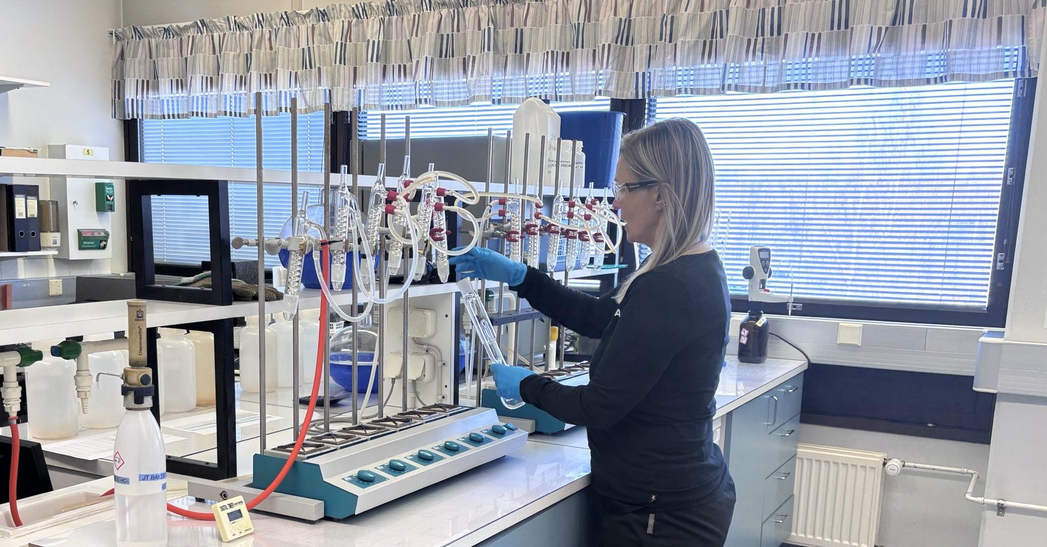 Voimalaitoskemian laboratoriossa nainen työskentelee näytteenottoputkien kanssa. 
